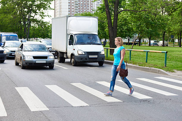 mujer cruzando la calle, en el cruce de peatones - crossing zebra crossing crosswalk street fotografías e imágenes de stock