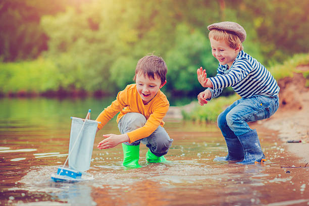 Children with toy ship Little boys with their toy ship near a lake in summer toy boat stock pictures, royalty-free photos & images