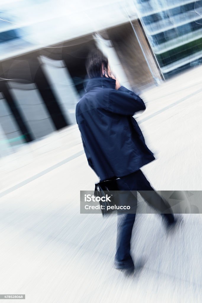 Businessman talking on mobile phone Young attractive businessman talking on mobile phone. Motion blurred commuters walking to work Business Stock Photo