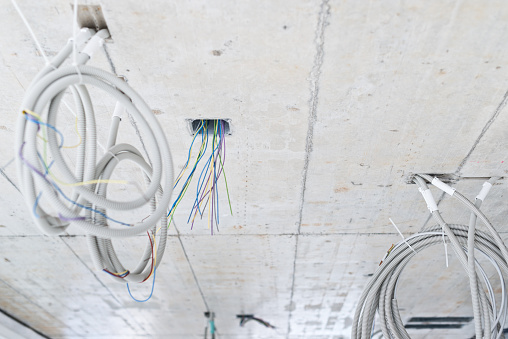 electric cables and tubes hanging from ceiling at construction site