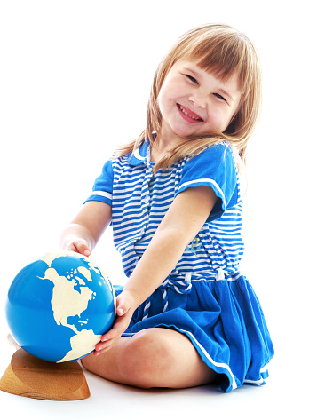 Curious girl sitting on the floor and exploring the globe-isolated on white background