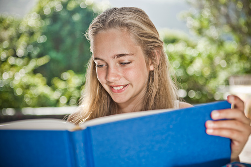 Smiling confident girl reading a blue book