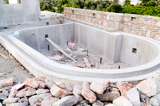 Swimming pool in a residential building under construction, raw cement and natural rocks