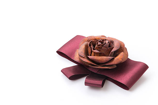 Tiny gift box with silk ribbon lie on rose heart shaped decoration made of man-made synthetic rose blossoms. Valentine day or engagement present idea, romantic love concept. Selective focus.