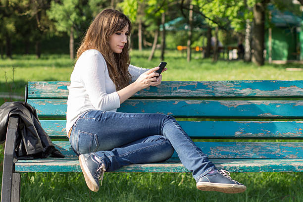 istock Pretty young woman using smartphone sitting on bench 478551648