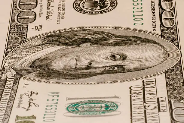 Close up of one hundred dollar bill lying vertically.