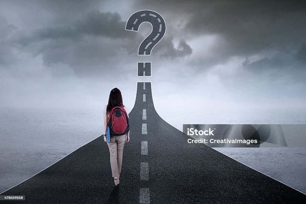 Student on the highway with question mark Female student walking on the street while carrying backpack with a question mark on the end Directional Sign Stock Photo