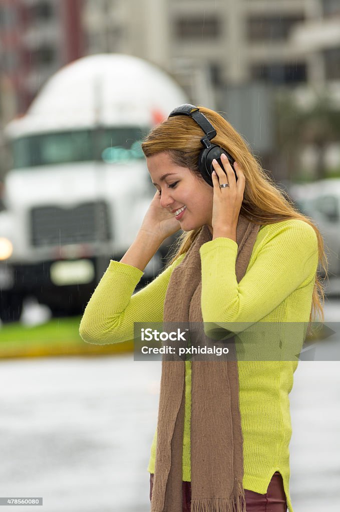 Woman outdoors listening to music Woman outdoors listening to music in casual clothing walking and holding hands over headphones 2015 Stock Photo