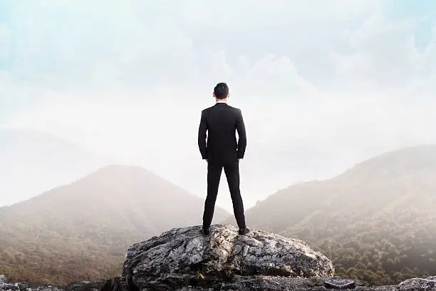Photo of Business man standing on the top of the mountain