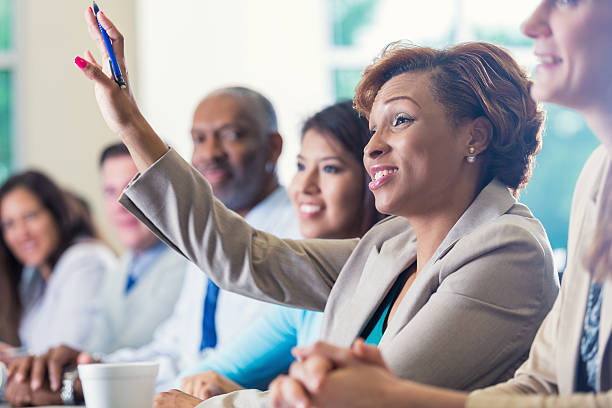afro-americana donna d'affari alzando le mani, ponendo domande in conferenza di lavoro - seminar asking business meeting foto e immagini stock