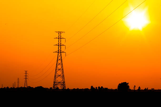High voltage power pole with orange sky stock photo