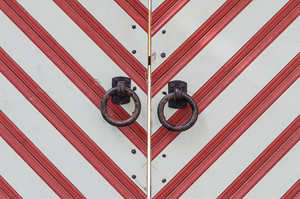 Old wooden red-white striped gate with rusty metal handles