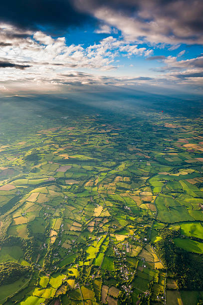 les rayons du soleil qui percent à travers les nuages sur le paysage champêtre idyllique vue aérienne - welsh culture wales field hedge photos et images de collection