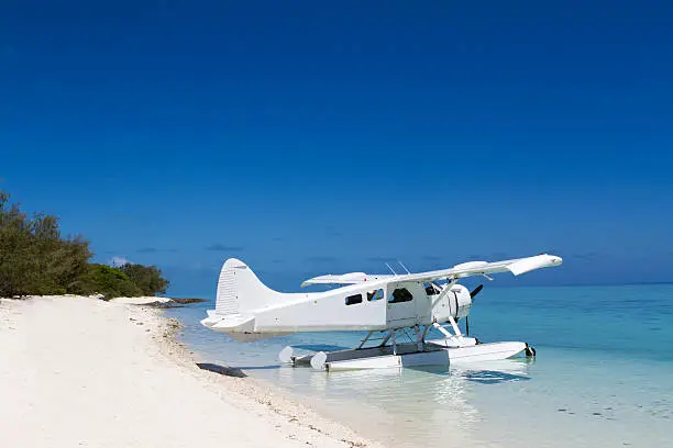White seaplane resting in the beautiful waters by the beach on a tropical island.