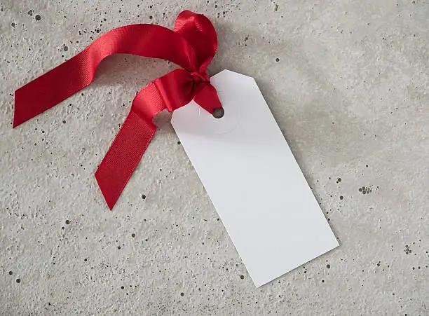 Gifttag, red ribbon, background concrete