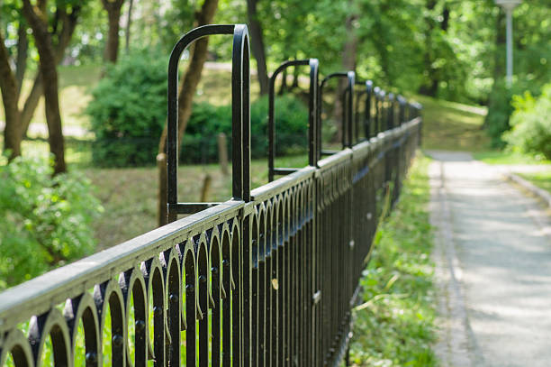 istock Vanishing decorative wrought iron fence in sunny park 478566506