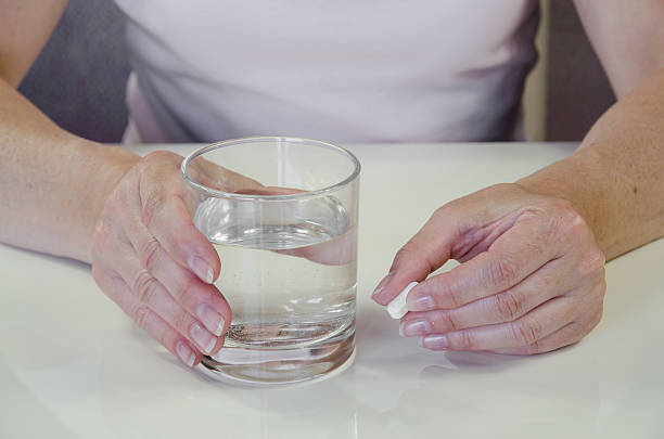 istock hand with pill and glass of water 478567250
