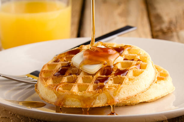 Waffles This s a photo of a couple waffles being soaked in syrup. Shot on a wooden table with a shallow depth of field. waffle stock pictures, royalty-free photos & images