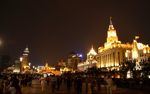 Shanghai, China - May 12, 2014: Crowd of tourists on the Bund at night, a scenic waterfront area in central Shanghai. It is one of the most famous tourist destinations in Shanghai and houses buildings of various architectures.