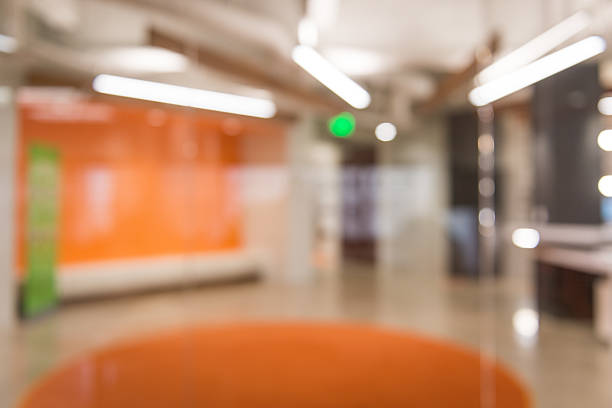 A blurry photograph of an office reception area with glass doors and overhead lighting background