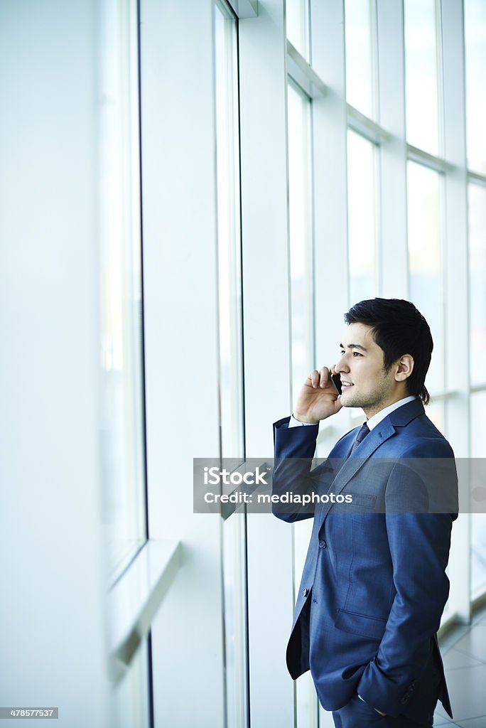 Manager on the phone Asian businessman talking on the phone and looking through window Men Stock Photo