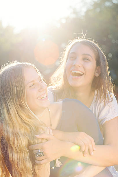 zwei teenager lachen im park - beauty in nature women beautiful human teeth stock-fotos und bilder