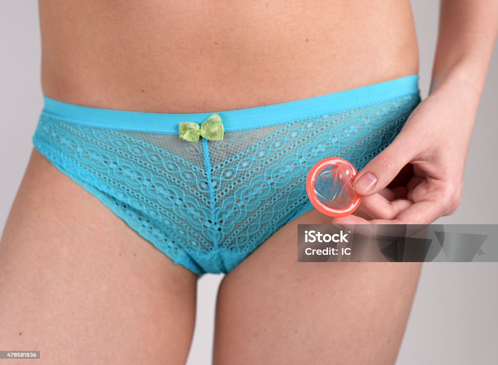 Safe Sex - Young woman in underwear holding condom Young woman in blue underwear is holding condom - Safe sex Underwear Stock Photo