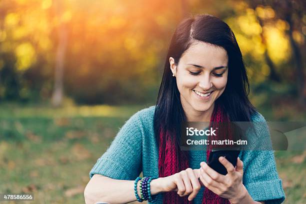 Girl Using Smartphone In The Park Stock Photo - Download Image Now - 20-29 Years, 2015, Adult