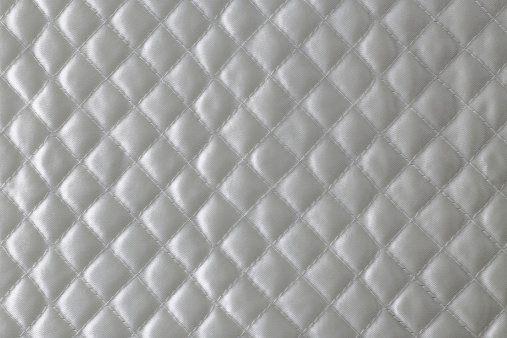 Stitch pattern of white quilted blanket.