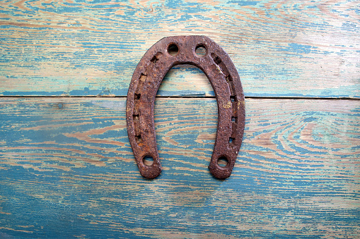 Old iron rusty metal horseshoe on weathered wood background