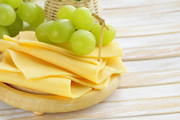 Woman slicing cheese at home in a wood board with grapes and crackers