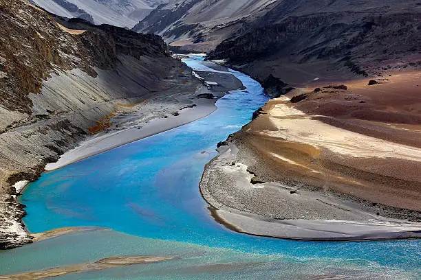 A gentle "S" shaped river appearing out of the depths of the Himalayan mountains captivate the eye. Nature manifests itself in all its  gorgeous hues, the Indus in an ethereal blue , the Zanskar River in  aqua green, the golden sands, mossy brown and rust coloured landscape. Nature's painting at its best!