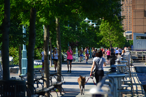 New York, USA - June 24, 2015: During a beautiful summer morning viewed over the Hudson River runners are seen passing by. Seen from Battery Park City Promenade, Lower Manhattan, New York City.