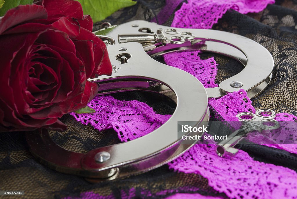 Handcuffs a pair of handcuffs with a red rose for the ladya pair of handcuffs with a red rose for the lady Authority Stock Photo