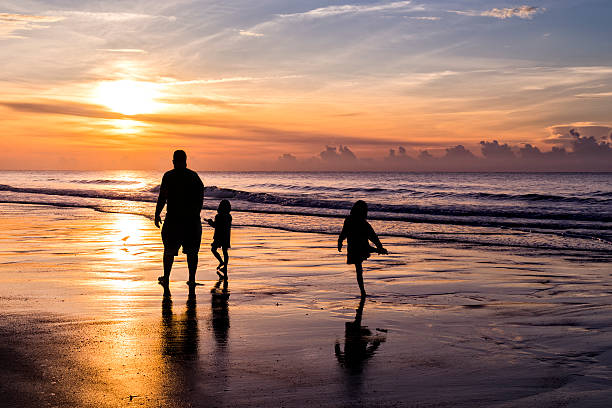 Garden City Beach, South Carolina, United States - June 11, 2015: Early morning beach activity in a happy vacation scene near Myrtle Beach, SC. Vacationers flock to the beaches near Myrtle Beach, South Carolina. This area is known as the Grand Strand for its wide, white beaches and warm ocean water. Morning walkers greet the sunrise.