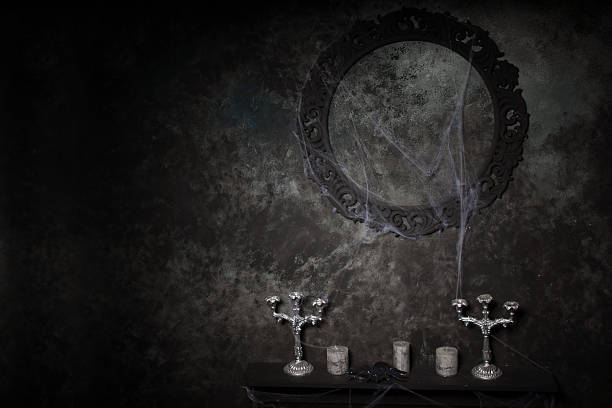 Candelabras and Empty Ornate Frame Covered in Cobwebs on Table in Eerie Halloween Haunted House Setting