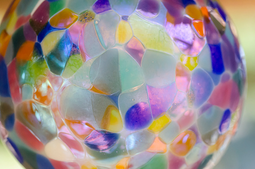 Extreme close up with shallow depth of field on a beautiful sphere of hand blown glass. Vibrant colors with various metallic, translucent and opaque areas.