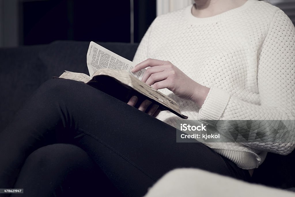 Christian woman reading the Bible Girl reading the holy bible at home. Sitting in sofa. Adult Stock Photo