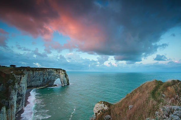 istock pink stormy sunrise over cliffs in ocean 478621965