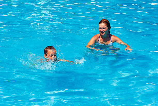 istock Mother train her son to swim in the pool. 478623339