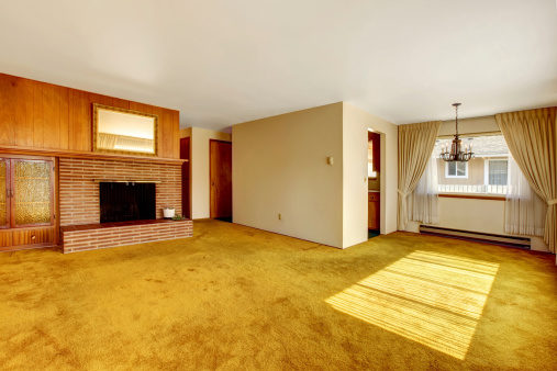 Empty bright living room with carpet floor, brick background fireplace and built-in cabinet
