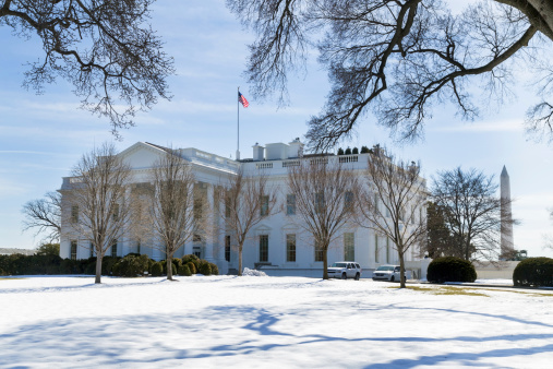 This is a front corner view of the White House in Washington, DC.  The Washington Monument is also visible behind and to the right of the house.