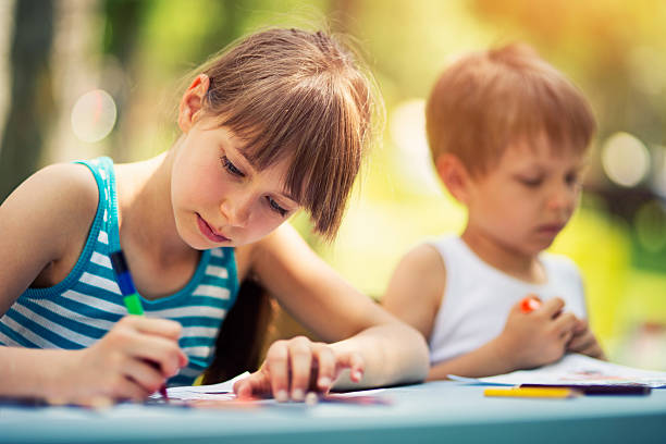 Sister and brother drawing together outdoows