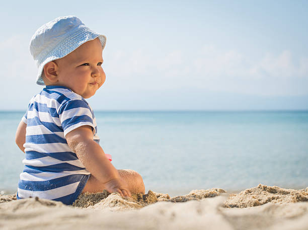 istock Baby boy with a hat sitting on the beach 478630664