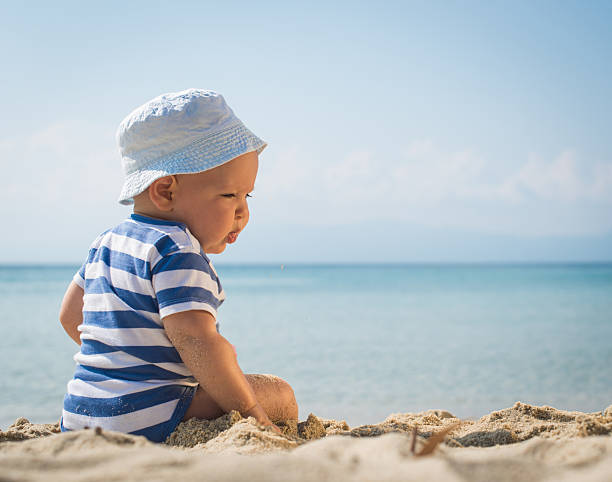 istock Caucasian baby boy with a hat sitting on sand 478630678