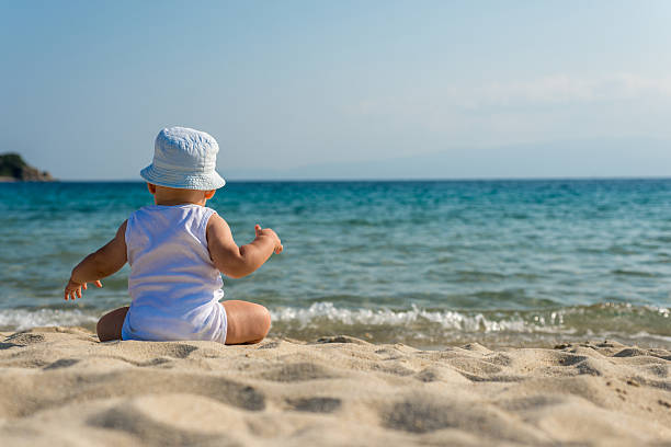 istock Caucasian baby boy with a hat sitting on sand 478630722
