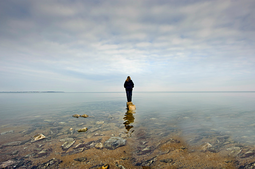 A person standing on a rock looking out over the Chesapeake Bay in Maryland surrounded by water