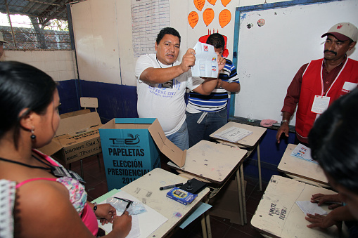 Tecoluca, El Salvador - February 2, 2014: A poll worker counting ballots displays one cast for the FMLN at the San Romilio school in the first round of the presidential election. There were three major candidates: Salvador Sanchez Ceren of the leftist FMLN party, Norman Quijano of the rightist ARENA party and Tony Saca of the centrist UNIDAD party.