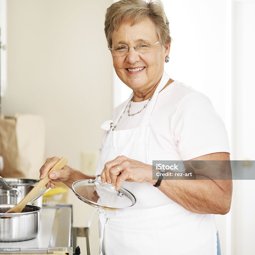 happy grandmother cooking in kitchen photo of a happy grandmother cooking in kitchen Grandmother Stock Photo