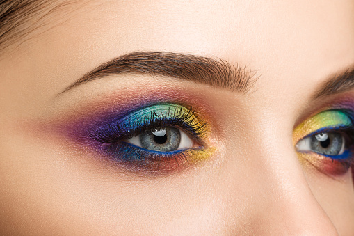 Close-up view of blue female eye with beautiful modern creative make-up